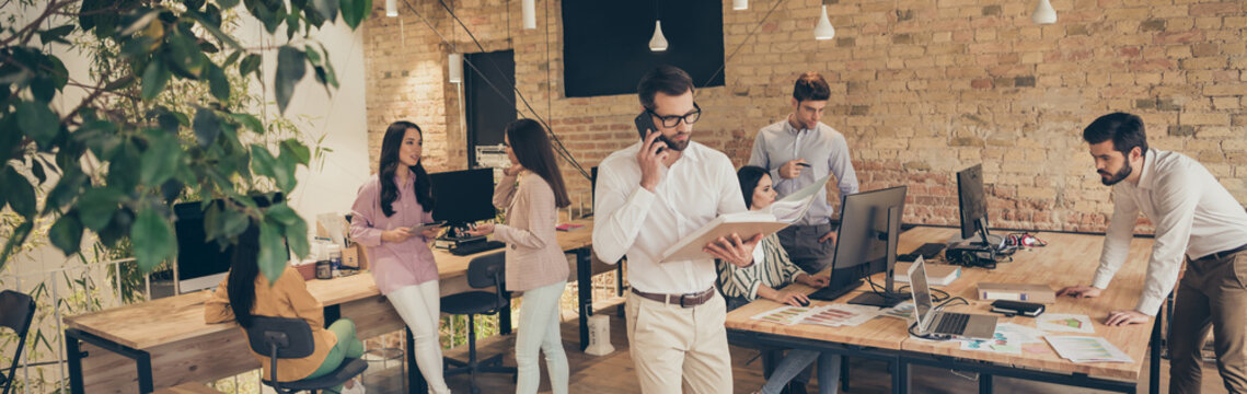 Nice confident experienced people director calling employee discussing document analysis at modern industrial loft brick open space style interior workplace workstation
