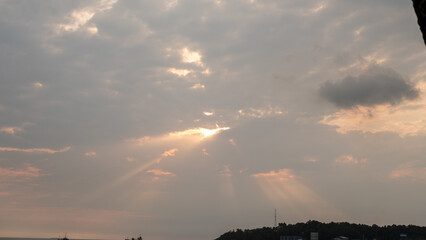 The sky during sunset with golden rays breaking through the clouds, illuminating the horizon. A...