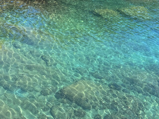 Ocean crystal clear water with stones and algae at the bottom.