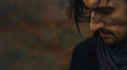 Unshaven Elegance - A close-up of a young man with flowing hair, draped in a coat and scarf,...