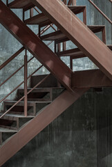 Vertical view of Old metal steps with handrails against concrete wall background. Side view of Steel ladder, Space for text, Selective Focus.