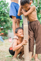 a child squats on a friend's step as a fulcrum during cooperation in a betel nut climbing...