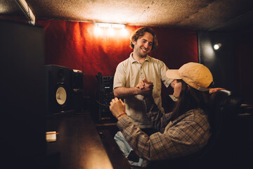 A musician and sound engineer, satisfied with their work, give each other a high five in a...