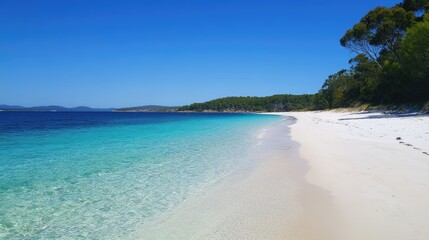 Obraz premium A white sandy beach with clear turquoise water under a bright blue sky.