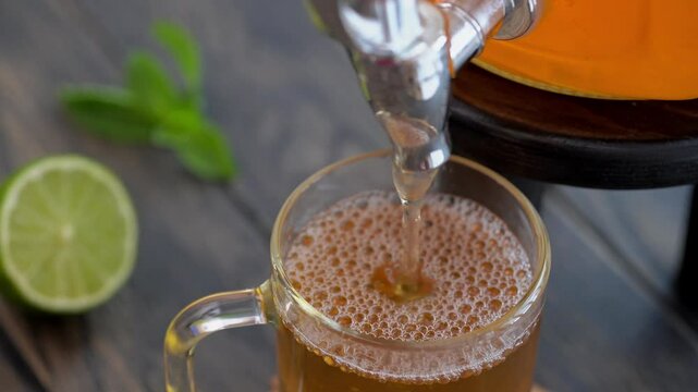 Pouring homemade kombucha fermented tea in glass.