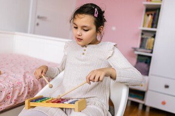Girl with autism plays metallophone. Music therapy at home