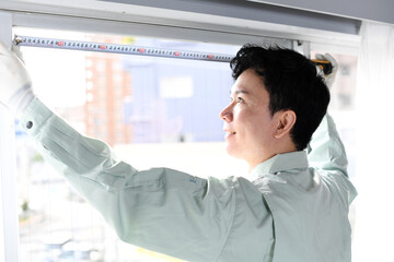 部屋の間取りを採寸するアジア人男性作業員