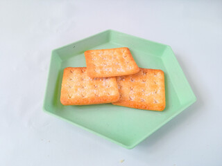 Sugar coated biscuits, also known as malkist, sweet and crispy. on a green hexagon plate isolate on white. snack concept