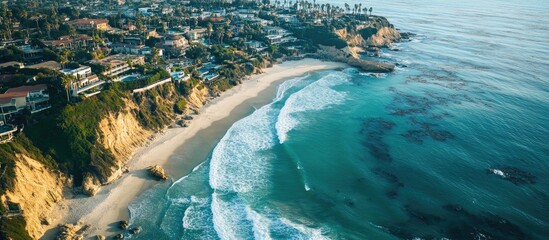 Fototapeta premium Aerial coastline view showcasing serene waves, sandy shore, and luxury homes along the majestic seaside landscape.