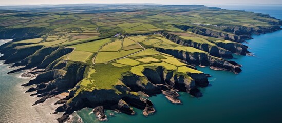 Aerial view showcasing the rugged beauty and lush landscapes of the South Pembrokeshire coast with dramatic cliffs and coastline.
