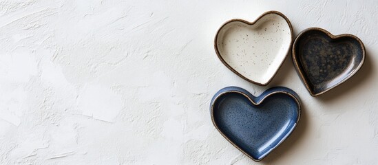 Obraz premium Heart shaped ceramic plates in varying colors arranged on a textured white background ideal for romantic or cooking themed imagery.