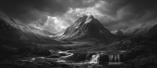 Majestic black and white landscape of Buachaille Etive Mor with dramatic clouds and serene waterfalls in the Scottish Highlands