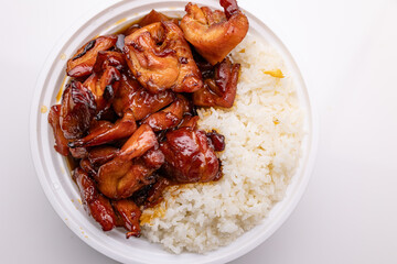 Top-down view of a plastic bowl containing Chinese takeout food: stir-fried chicken glazed with bourbon sauce, served alongside white rice.