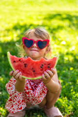 Child eating watermelon in the garden. Selective focus.