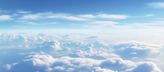 Fototapeta premium Aerial view of fluffy white clouds under a bright blue sky from an airplane window