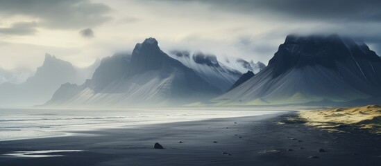 Stokksnes Beach panorama showcasing dramatic mountains and serene black sand landscape with ocean waves under moody skies