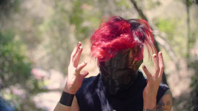 A man with vibrant red hair and face wrapped in black tape shakes his head intensively, as if in anger, rage or despair, creating a surreal and unsettling appearance. A metaphor of madness and frenzy