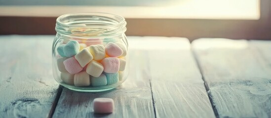 Marshmallows in a glass jar on a light wooden surface with a vintage design creating a cozy and inviting atmosphere for candy lovers