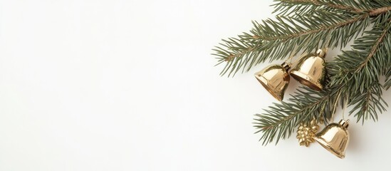 Obraz premium Golden jingle bells nestled in a pine branch creating a festive holiday atmosphere on a clean white background