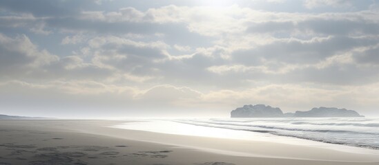 Tranquil deserted beach with silvery sunlight reflecting on calm waters under a cloudy sky creating a serene atmosphere.
