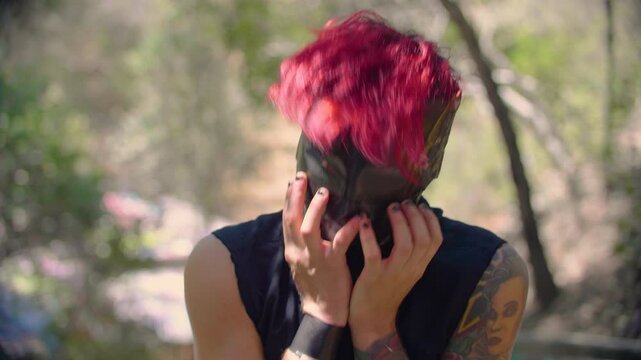 A man with vibrant red hair and face wrapped in black tape shakes his head intensively, as if in anger, rage or despair, creating a surreal and unsettling appearance. A metaphor of madness and frenzy