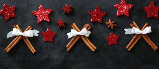 Cinnamon sticks white bows and red sequins arranged on a dark surface for festive holiday decoration concept aerial view