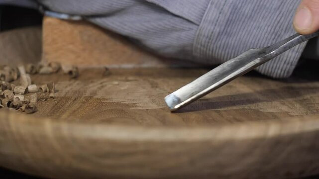 a woodcarver cuts a walnut plate, the sounds of the cutter are heard