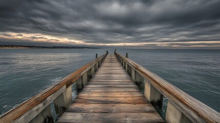 Obraz premium A serene wooden pier extending into a calm sea under a dramatic cloudy sky.