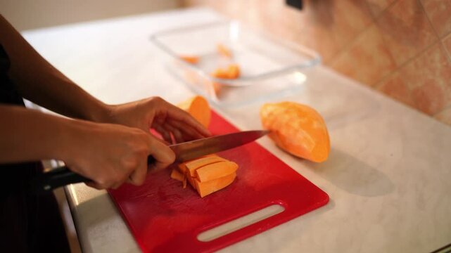 Housewife cuts raw sweet potato into strips on a cutting board on the table. High quality 4k footage