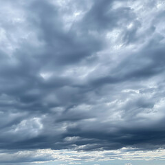 Obraz premium A dramatic sky with sun rays piercing through gaps in massive white clouds