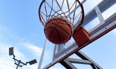 Basketball ball and basketball hoop outdoors on sky background. © Angelov