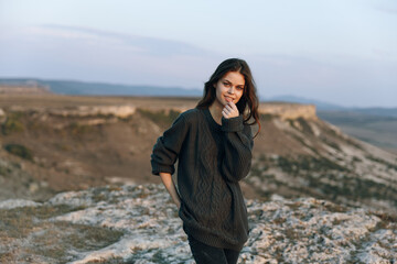 Naklejka premium Woman in black sweater standing on hill overlooking majestic mountains in peaceful solitude