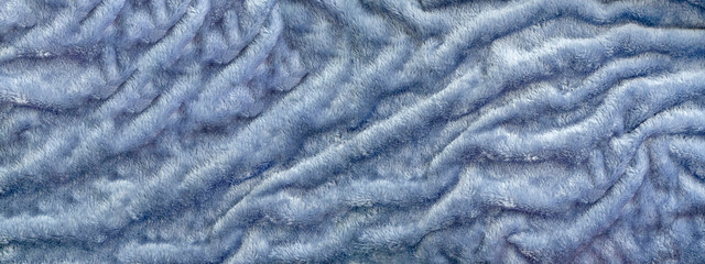 Textile abstract long background with faux fur. Gray-blue faux fur texture with numerous folds.