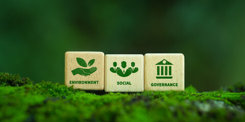 Green ESG icon on wooden block. Environment, social and governance concept. Net zero greenhouse gas emissions for a sustainable global environment. On a green forest background.