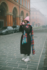 A woman is capturing beautiful photos while walking through a foggy and mysterious city street
