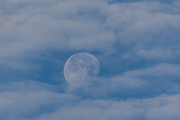 waning moon hiding in the morning between clouds