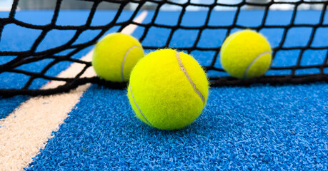  paddle tennis balls near the lines of a blue paddle tennis court, racket sports concept