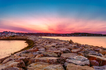 Dramatic colorful sunset sky with rocks in foreground in Rockport, Massachusetts, US