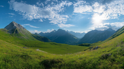 Obraz premium Beautiful green meadow with mountains in the background, a sunny day panorama. Panoramic landscape of the Alps mountain range in the summertime 