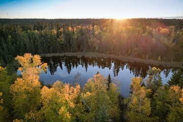 A lake surrounded by trees with a beautiful sunset in the background
