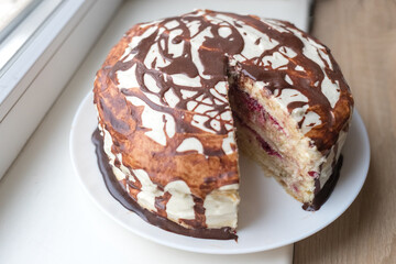 Chocolate pie Milchmadchen with cheese cream sauce with banana and cherry on the windowsill. Traditional German cake. Ready to eat.