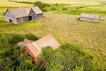 A rural area with three old buildings and a field of grass