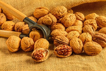 Walnuts with nutcracker on burlap fabric.