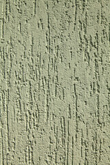 Green faded surface, texture, background. Decorated surface with vertical embossed strokes or stripes. Pale, light-green wall surface with abstract pattern. Embossed plastering of building wall