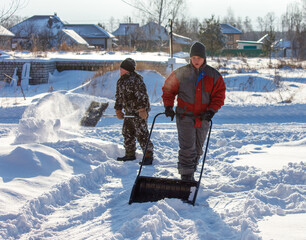 Two men are shoveling snow with a snow plow