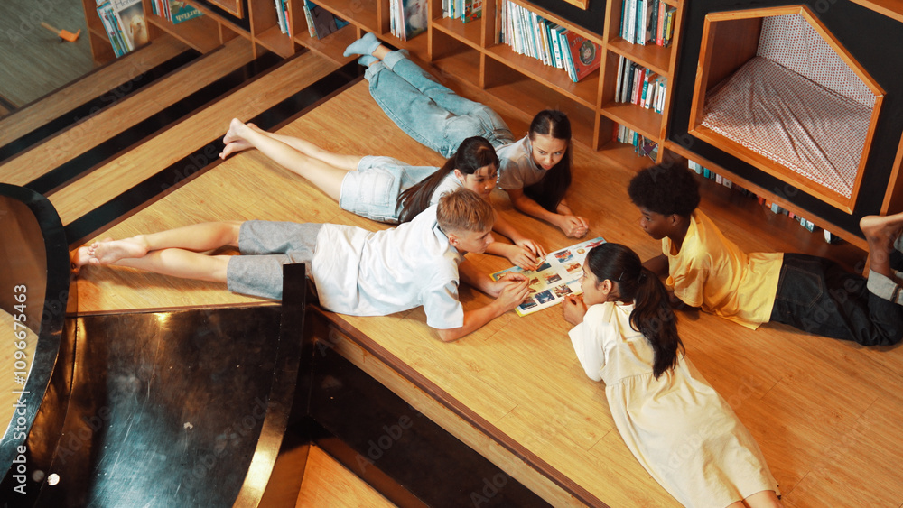 Poster group of diverse children lying down in circle while reading a book at library. top view of girl sha