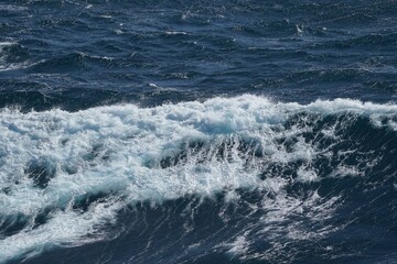 Waves crashing on ocean surface, creating dynamic and vibrant scene. deep blue water contrasts with white foam, evoking sense of power and tranquility