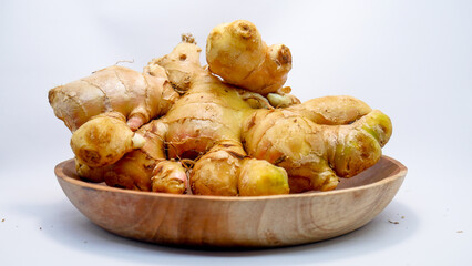 fresh ginger root arranged on a wooden plate against a clean white background