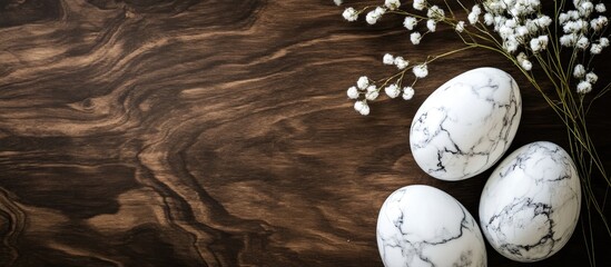 Elegant marble Easter eggs on rustic wooden surface with delicate floral accents for a stylish holiday decoration backdrop.