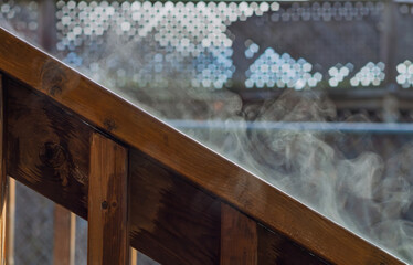 Sun evaporating the rain off the wooden railing 